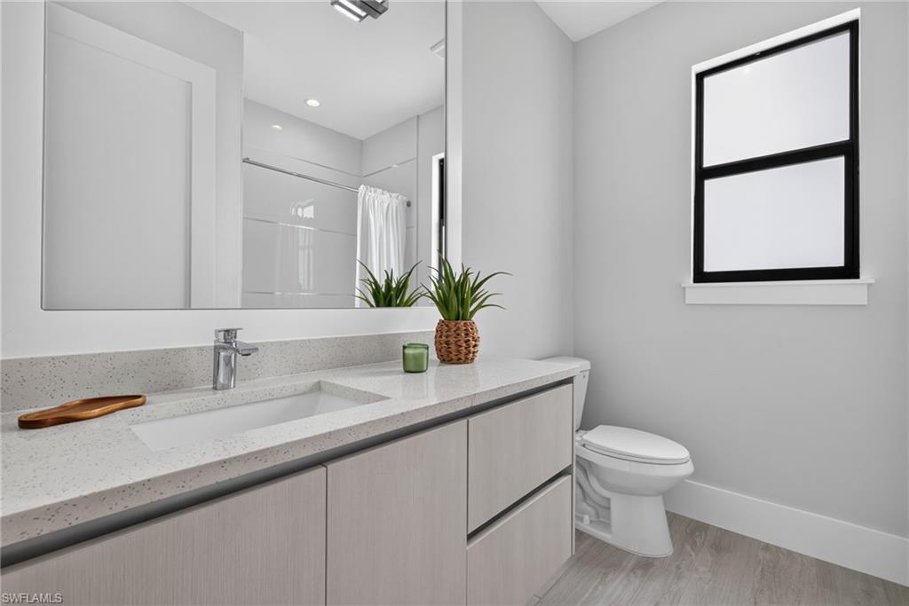 Floating vanity with a light-toned wood-finish, integrated rectangular sink, and speckled countertop