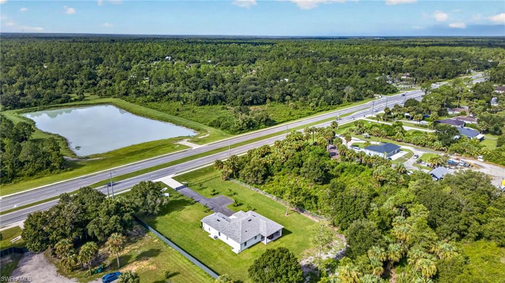 Expansive property featuring a large body of water, direct road frontage, a paved driveway, and surrounding green space