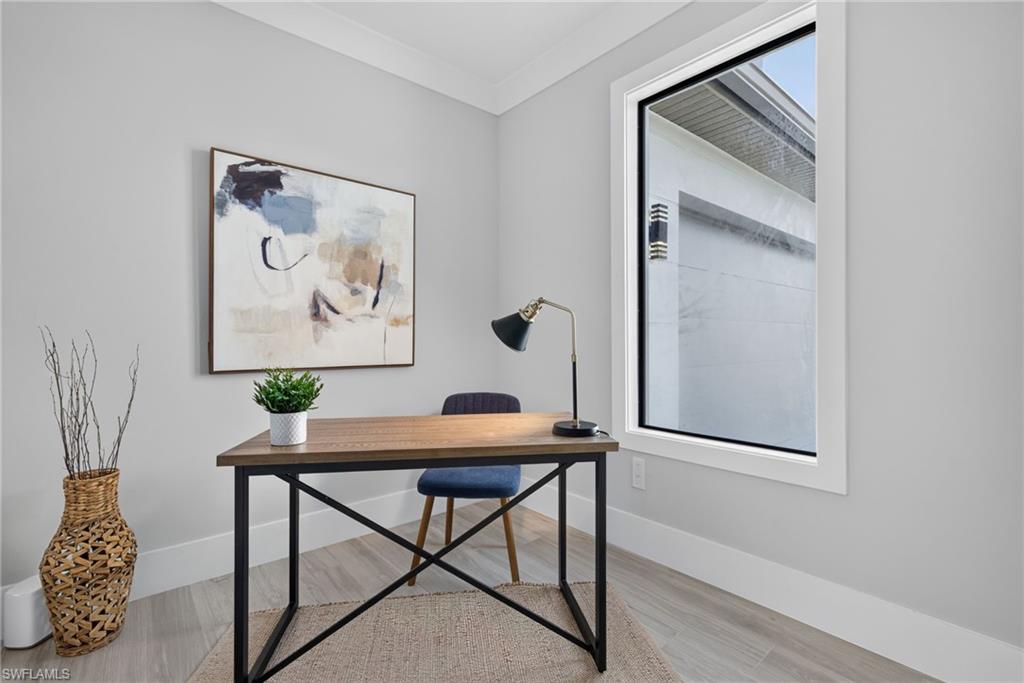 White trim window, light gray wall finish, crown molding, and wood-finish flooring