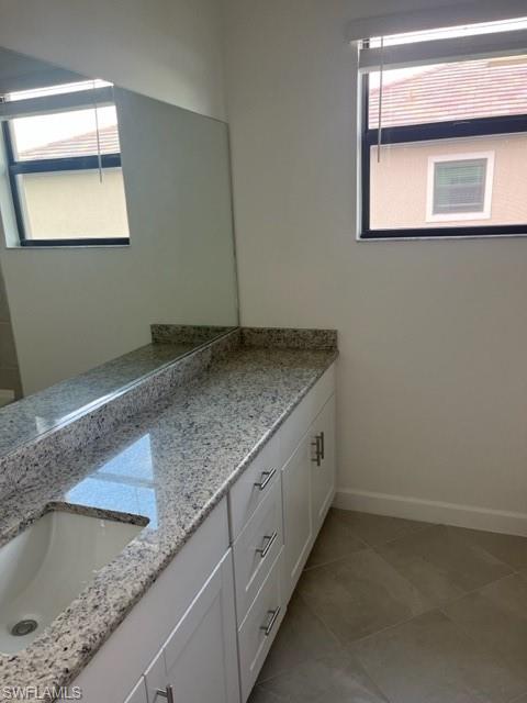Bathroom featuring double vanity, baseboards, and tile patterned floors