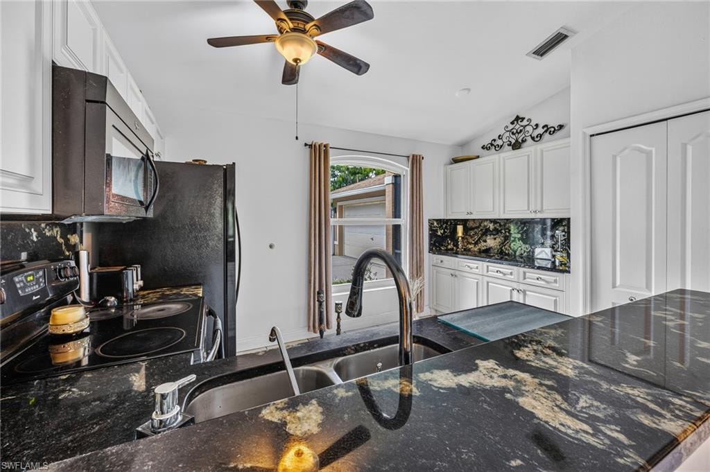 Kitchen featuring black granite countertops with integrated double sink, white cabinetry, and a ceiling fan with light fixture