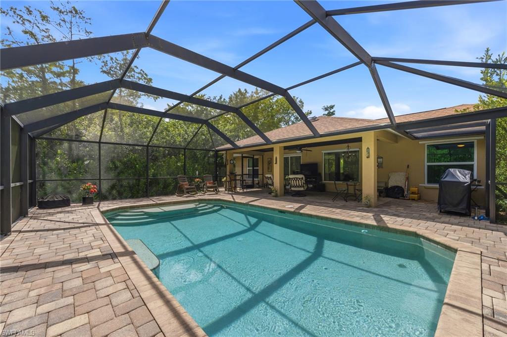 Screened-in pool with paver decking, integrated steps, and an expansive covered patio