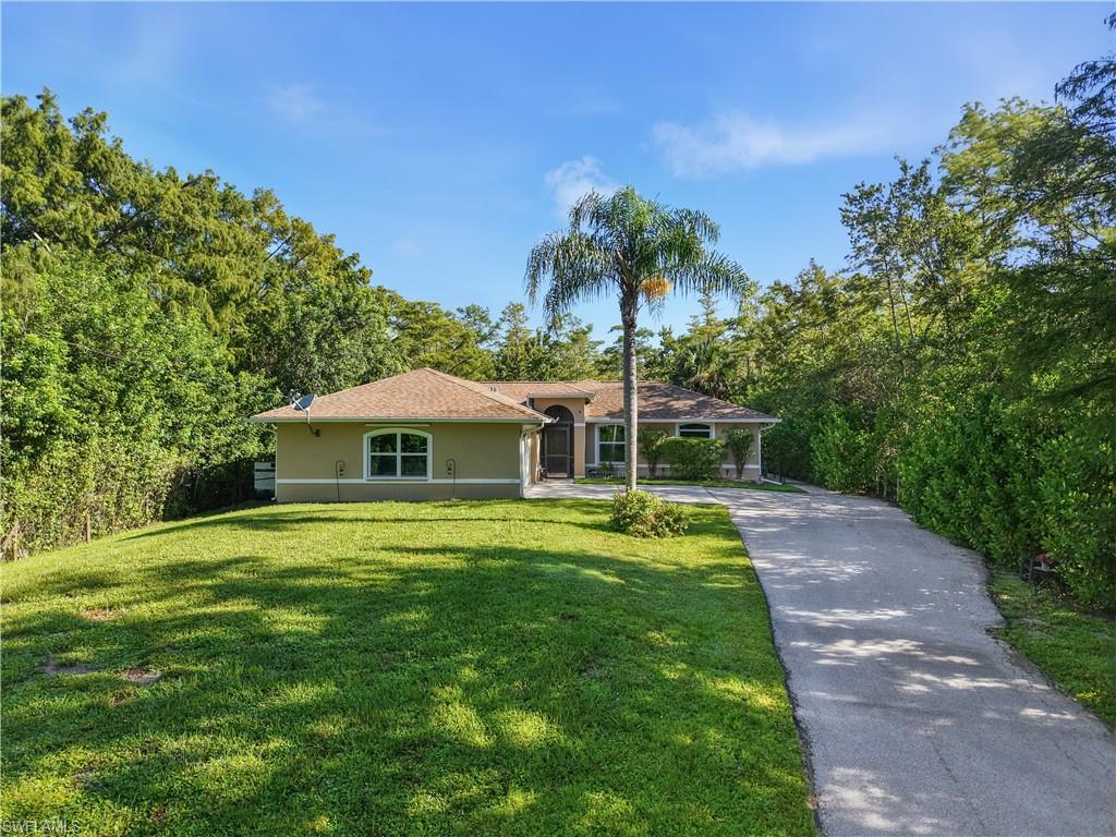Stucco exterior with a shingle roof, arched entryway, and a paved driveway
