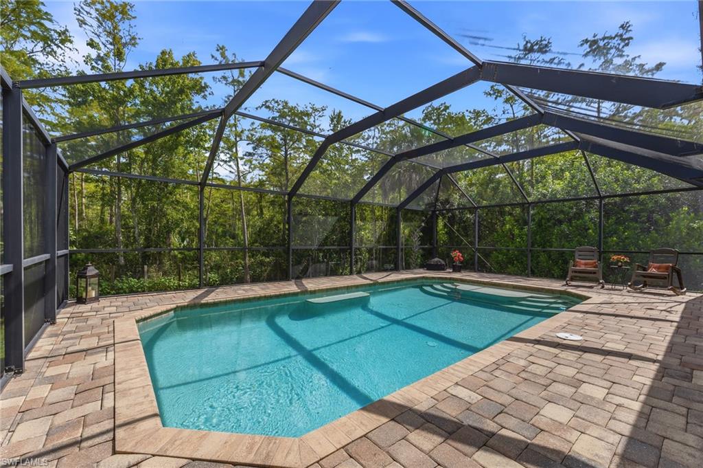 Screened enclosure featuring a geometric swimming pool with integrated steps, surrounded by paver decking
