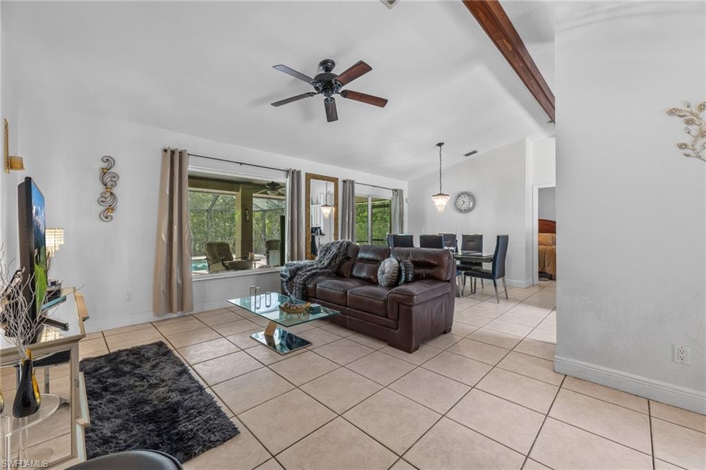Vaulted ceiling with exposed wood beams, tile flooring, and ceiling fan