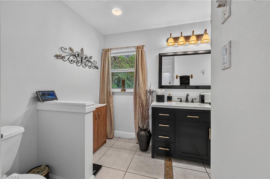 Black vanity with gold-tone hardware, white countertop, and tiled flooring