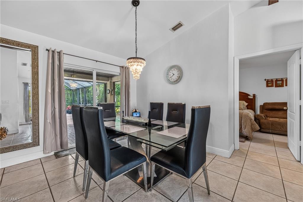 Tile flooring, vaulted ceiling, glass sliding doors, screened enclosure, and a crystal chandelier
