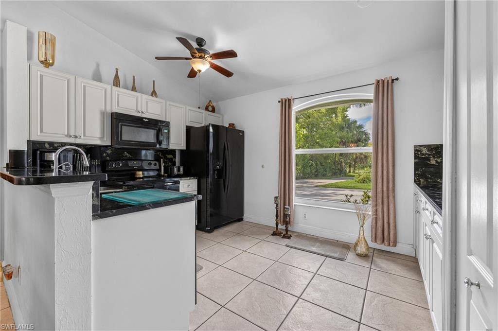 White cabinetry, black appliances, black countertops, ceiling fan, and tiled flooring