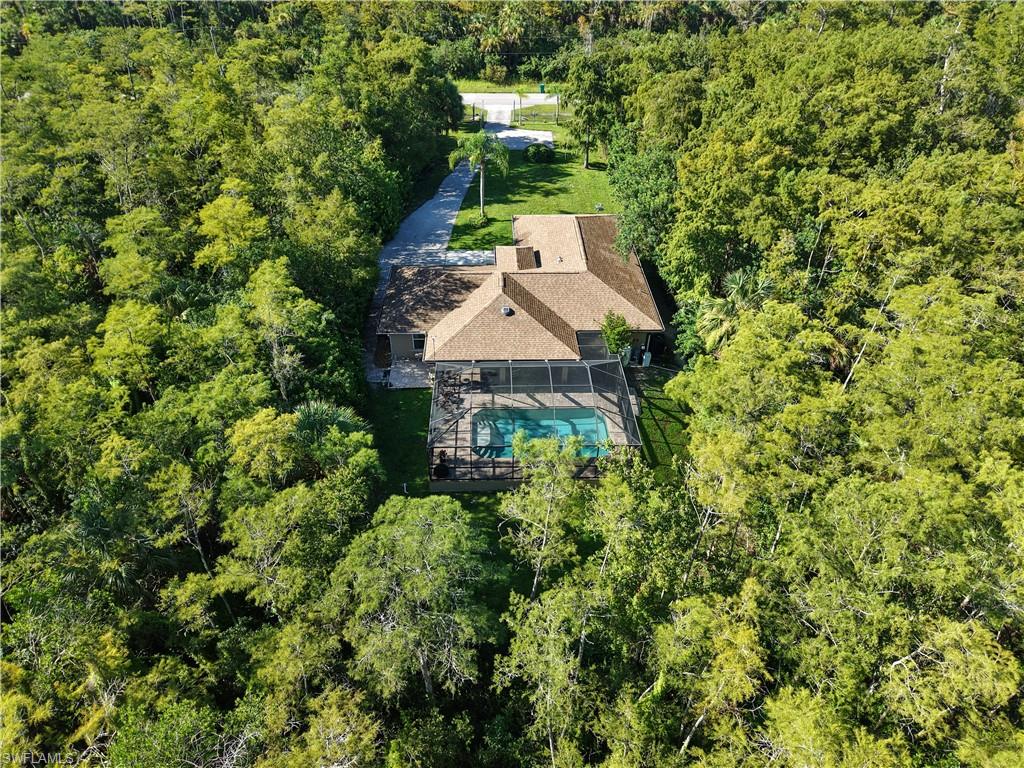 Property surrounded by mature trees, featuring a private swimming pool with a screened enclosure