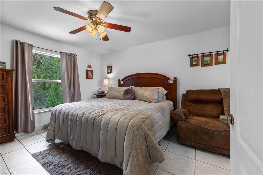 White walls, ceiling fan with integrated lighting, window with exterior landscape, and tiled flooring