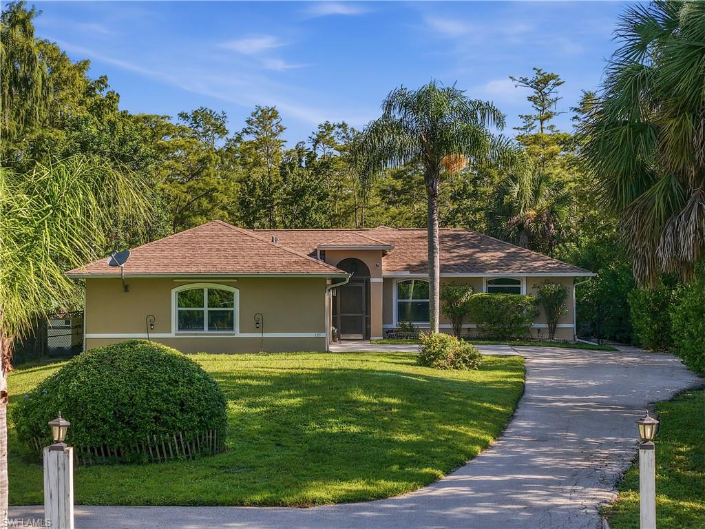 Stucco exterior residence with an arched entryway, shingle roof, and a paved driveway