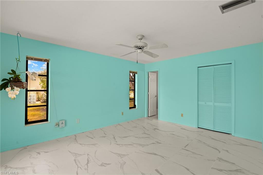 White and gray patterned tile flooring, ceiling fan, bi-fold louvered closet doors, and recessed windows
