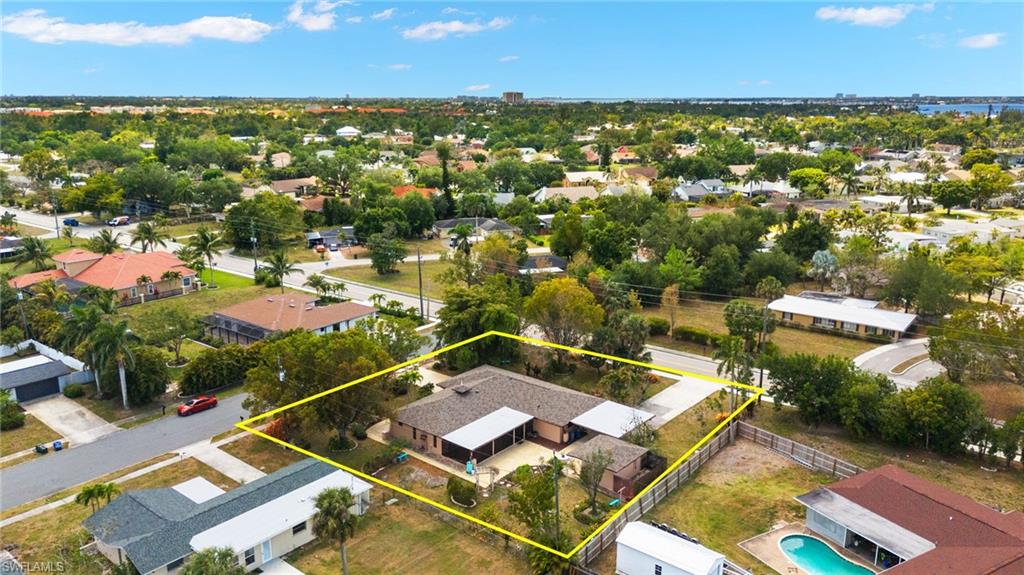 Aerial perspective of a property featuring a single-story residence with an attached covered carport and a detached shed