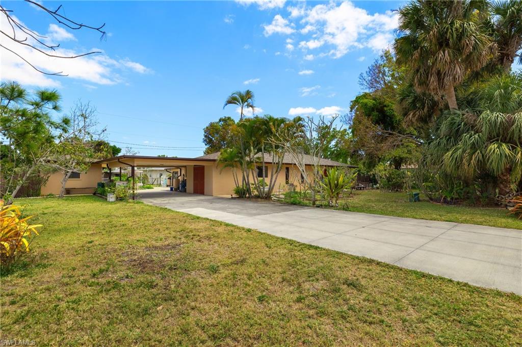 Exterior featuring a stucco finish, attached carport, mature palm trees, and a concrete driveway