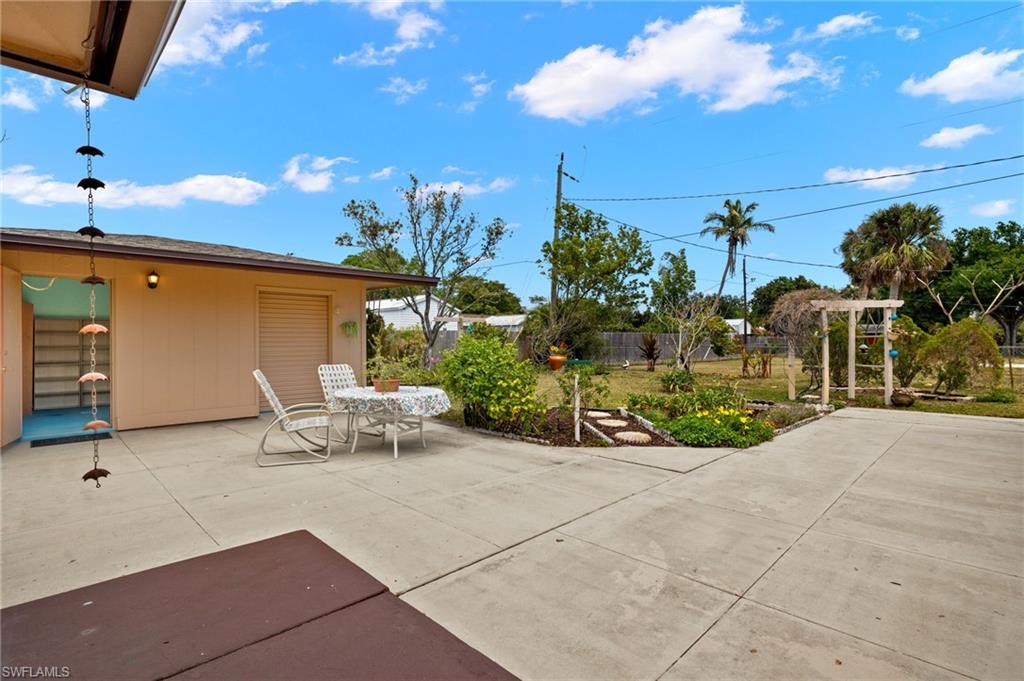 Expansive concrete patio area with a distinct garden bed featuring a stepping stone path and a decorative arbor structure
