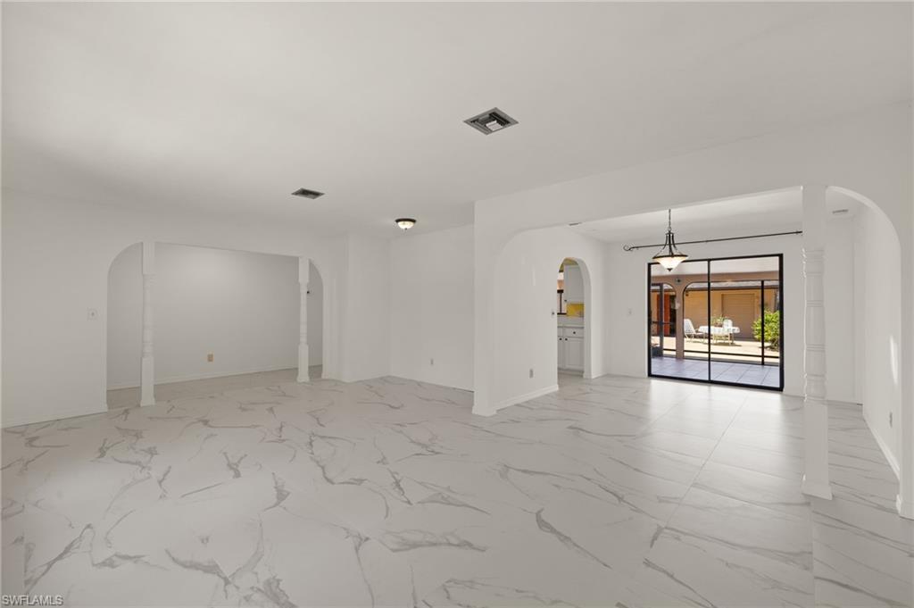 Expansive interior with large format tile flooring, arched doorways, and a black-framed sliding glass door
