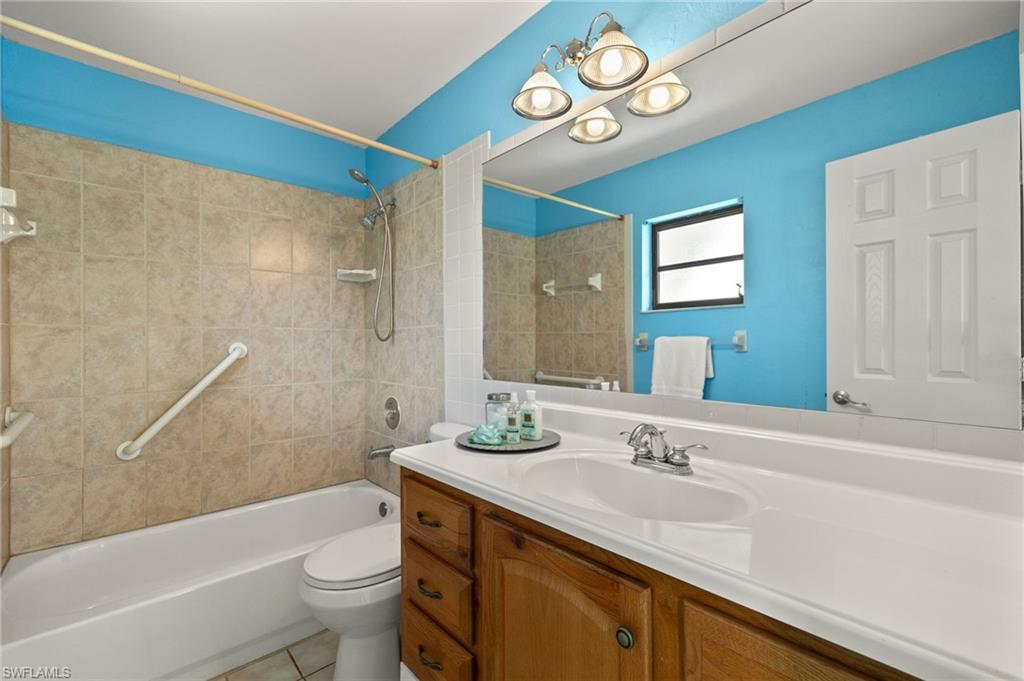 Bathroom featuring a tiled shower surround, built-in bathtub, wood-finish vanity, and a large mirror