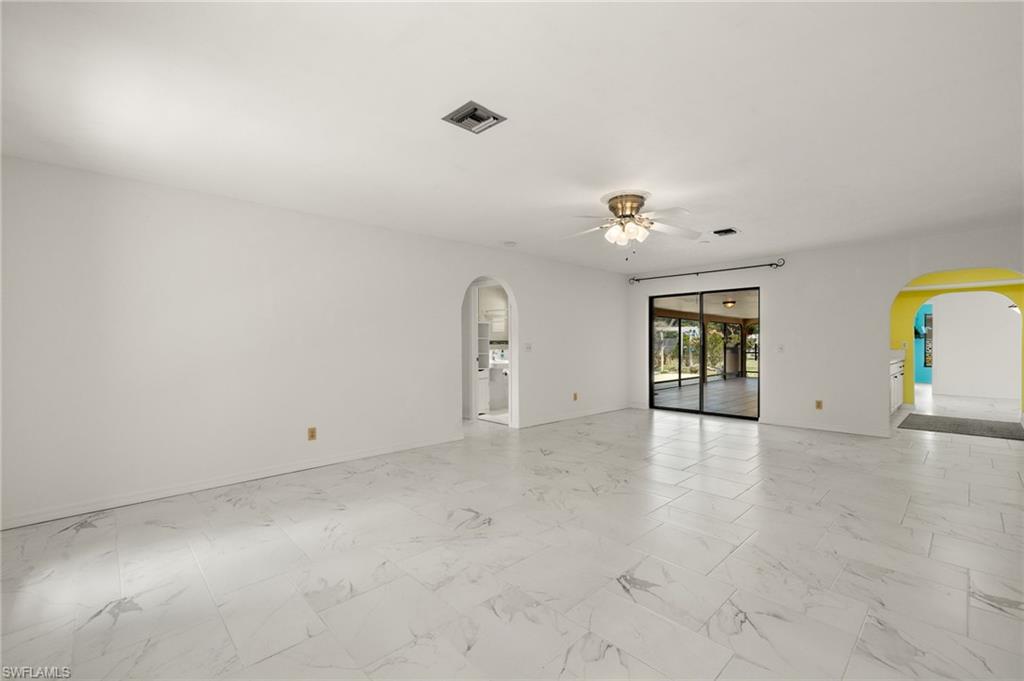 White tile flooring throughout the room, arched doorways, and a ceiling fan with integrated lighting