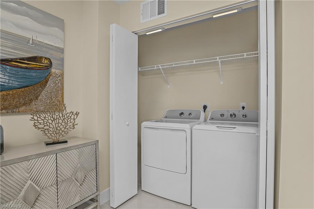Integrated laundry closet featuring a washer and dryer, convenient wire shelving, and overhead lighting
