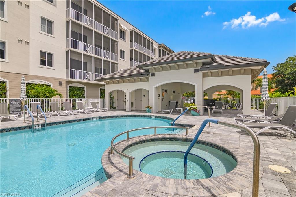 Resort-style pool area featuring a built-in spa, paver decking, and a covered cabana