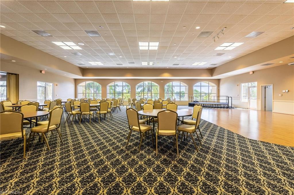 Expansive event space featuring patterned carpeting, wood-finish flooring, recessed lighting, and multiple arched windows