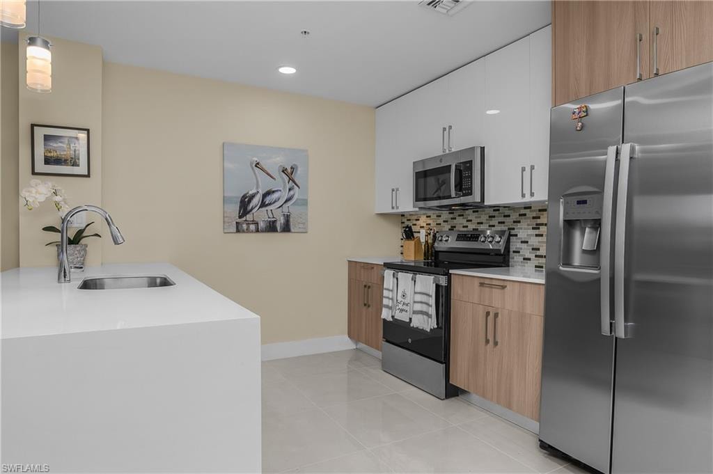 Modern kitchen featuring a waterfall countertop with an undermount sink and a gooseneck faucet