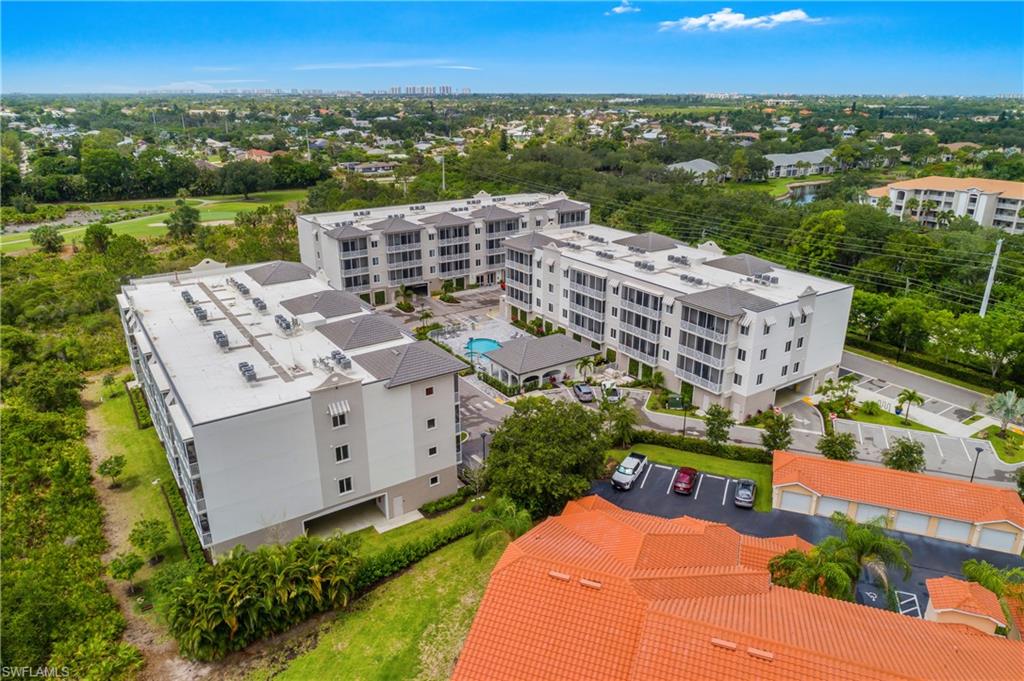 Multi-story residential buildings featuring covered balconies, a central swimming pool, and dedicated surface parking