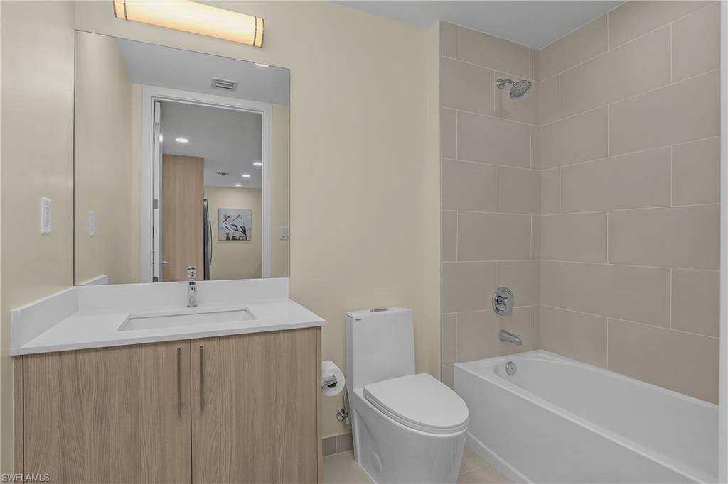 Wood-finish vanity with a white countertop and integrated sink, chrome faucet, and a large wall-mounted mirror