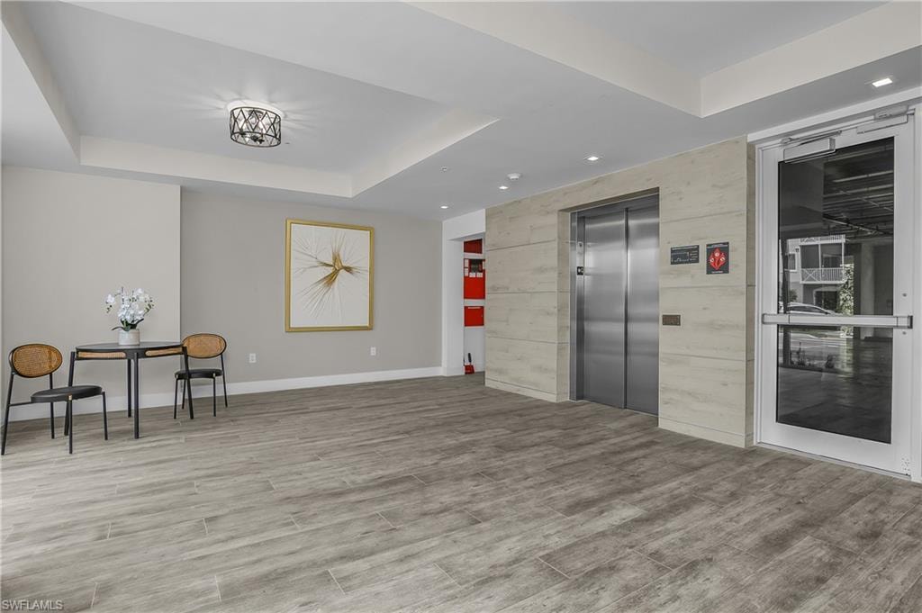 Modern lobby featuring wood-finish flooring, stainless steel elevator, and recessed ceiling lighting
