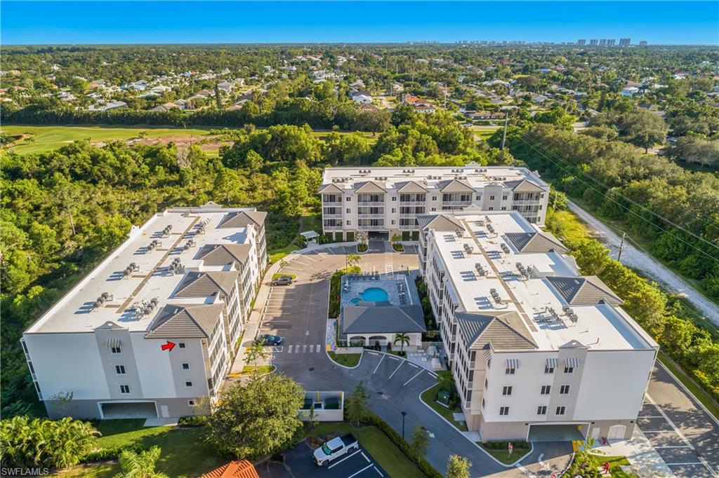 Modern stucco exterior with multiple balconies, covered parking, and an exterior amenity space featuring a swimming pool