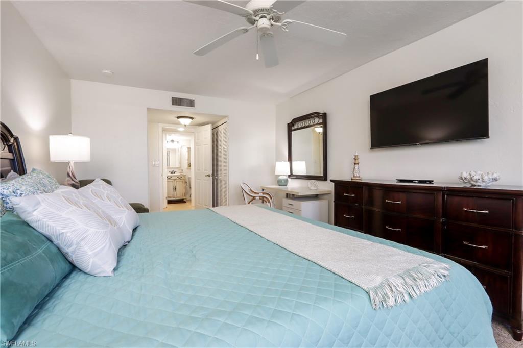 Bedroom featuring ensuite bathroom, a closet, a ceiling fan, and carpet floors