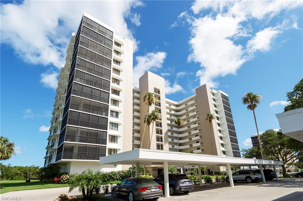 View of apartment building / complex featuring covered parking