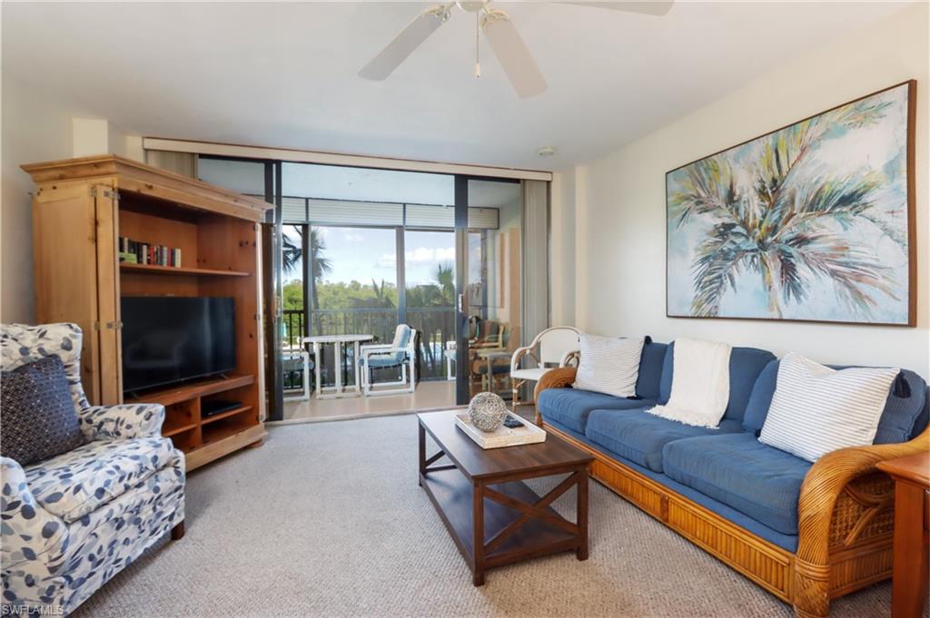 Carpeted living area featuring ceiling fan and a wall of windows