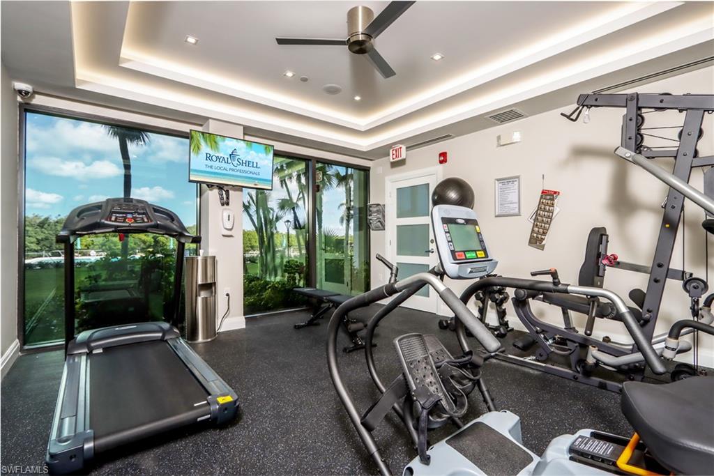 Exercise room with ceiling fan, a raised ceiling, baseboards, and recessed lighting