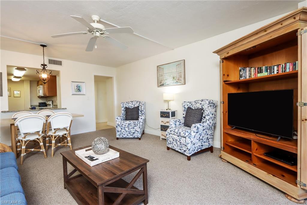 Carpeted living area featuring a ceiling fan and baseboards