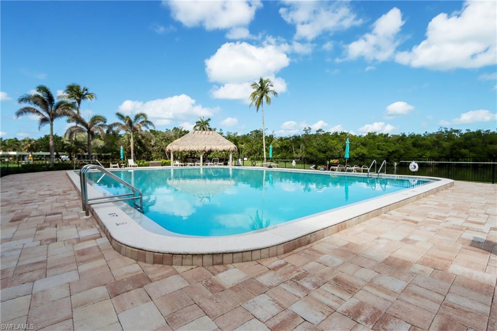 Community pool featuring a gazebo, a patio, and view of wooded area