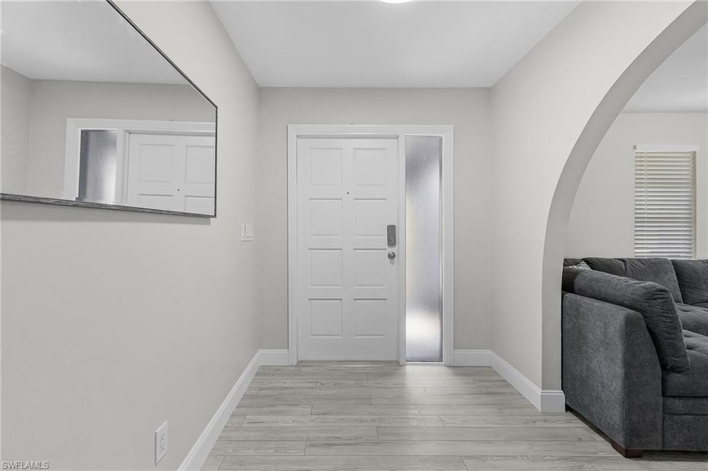 Wood-finish flooring throughout, arched entryway, recessed ceiling lighting, and a chandelier in the dining area