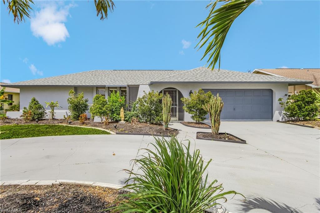 Light gray exterior with a gray garage door, concrete driveway, and landscaped front yard
