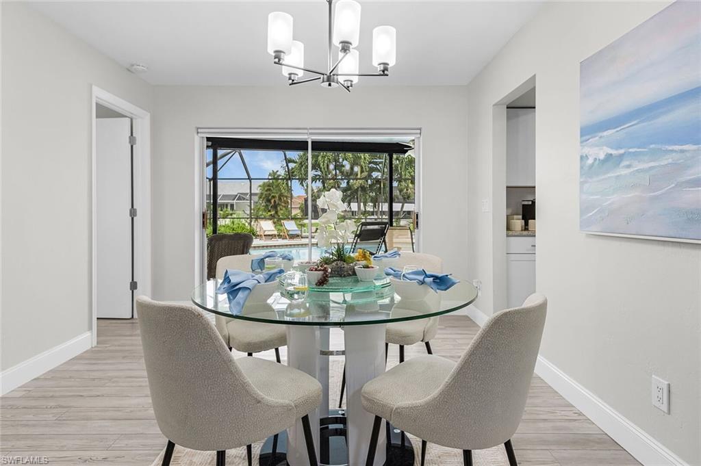 Recessed lighting, contemporary chandelier, sliding glass doors, light wood-finish flooring, and white baseboards