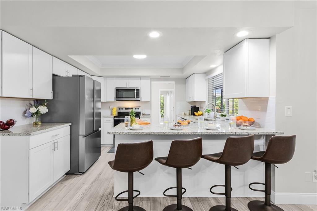 Kitchen featuring white cabinetry, light-toned countertops, a stainless steel refrigerator, and recessed lighting