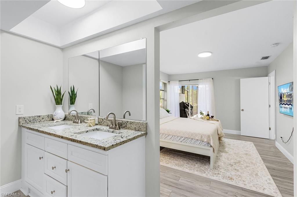 Dual vanity with undermount sinks, stone countertop, brushed nickel fixtures, and a large wall-mounted mirror