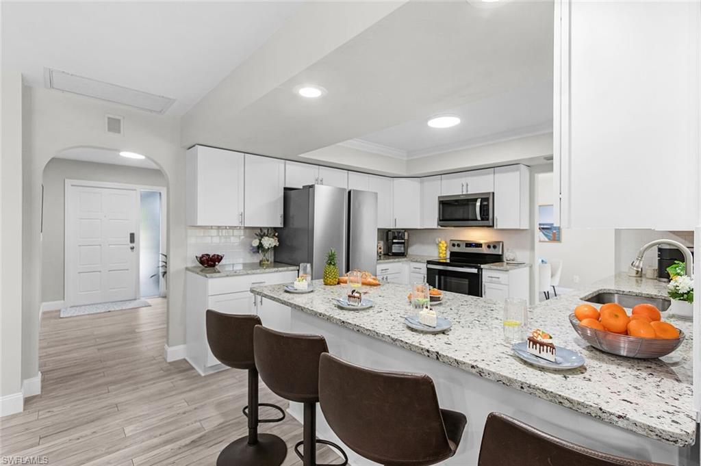 Laundry area with stacked appliances, a utility sink with white cabinetry, wood-finish flooring, and a window with blinds