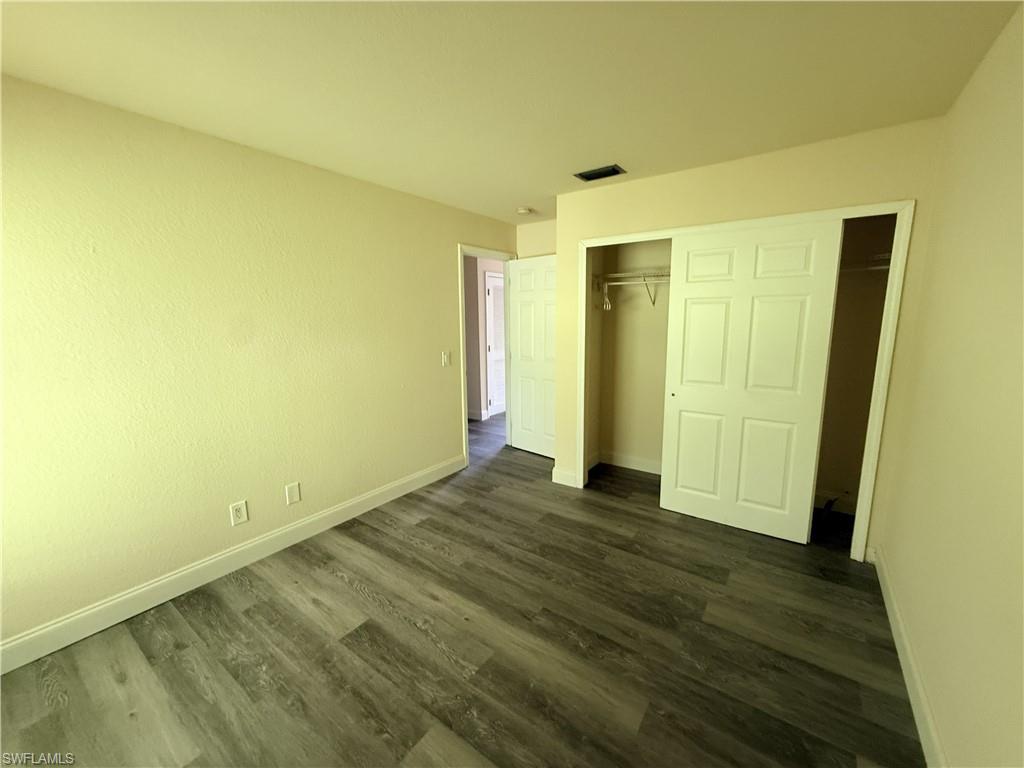 Neutral-toned walls, wood-finish flooring, white trim, and a white sliding closet door