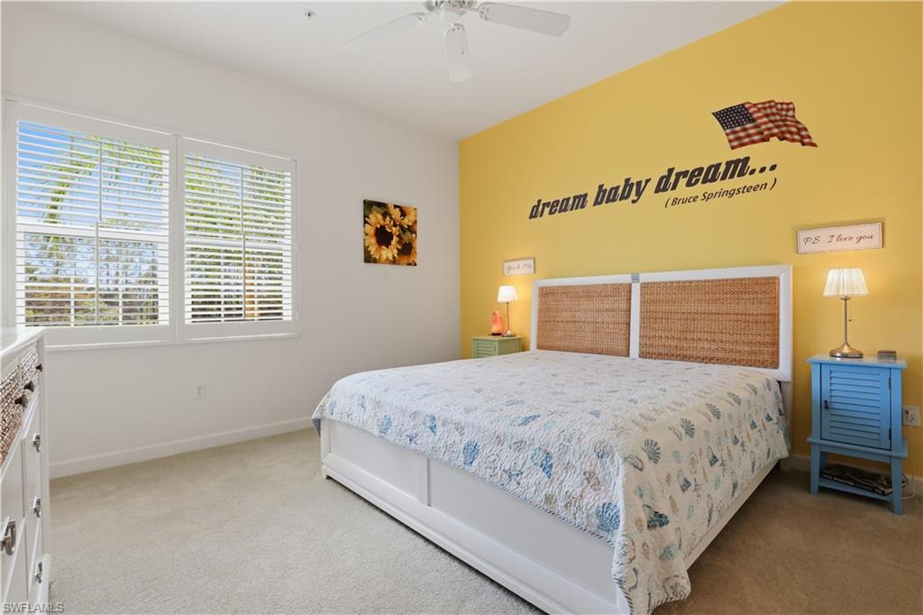 Carpeted flooring paired with a white ceiling fan and dual windows
