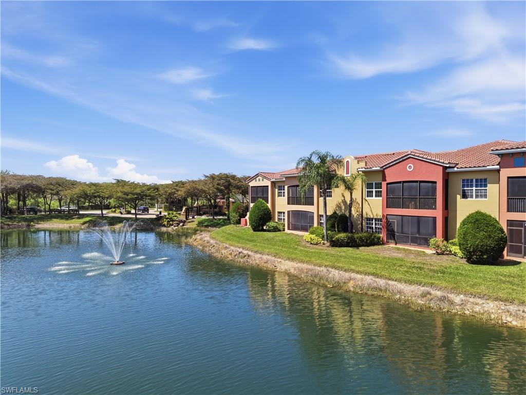 Waterfront property featuring a fountain, mature trees, and vibrant exterior paint