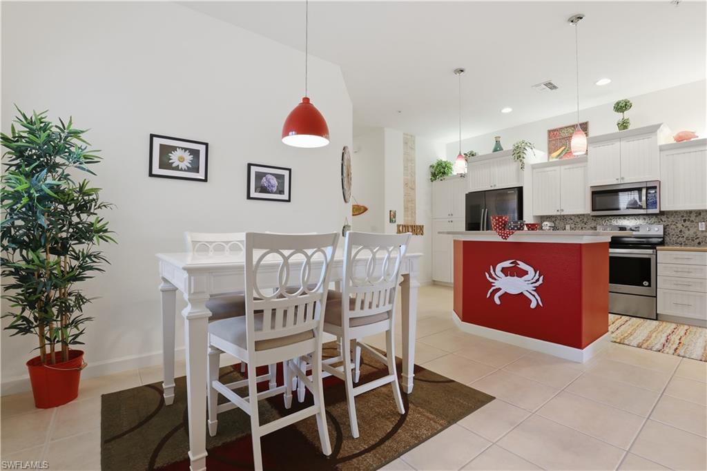 Open-concept living space featuring a dining area, kitchen island with seating, pendant lighting, and stainless steel appliances