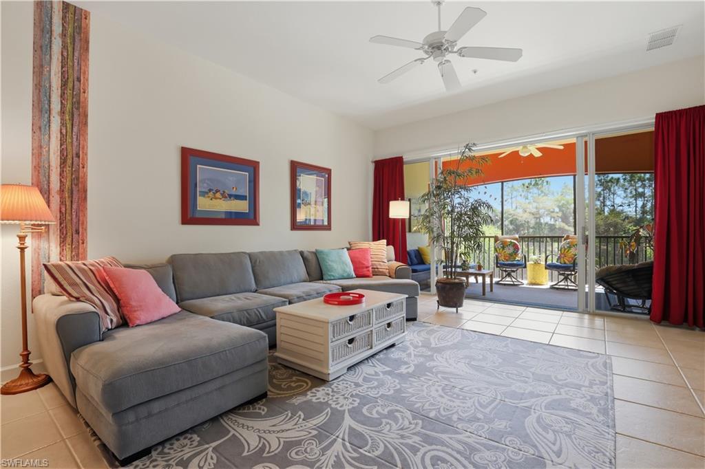 Living area with tile flooring, a ceiling fan, and a wide sliding glass door leading to a screened balcony
