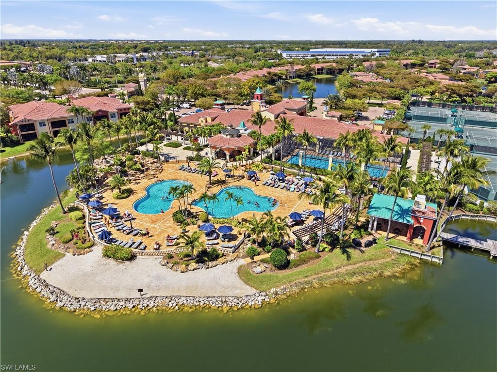 Expansive aquatic recreation area featuring two large pools, surrounding lounge space, and mature palm trees