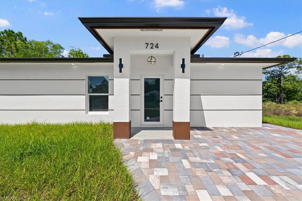 Contemporary exterior design with a flat roof, multi-tone paver driveway, and a prominent entry