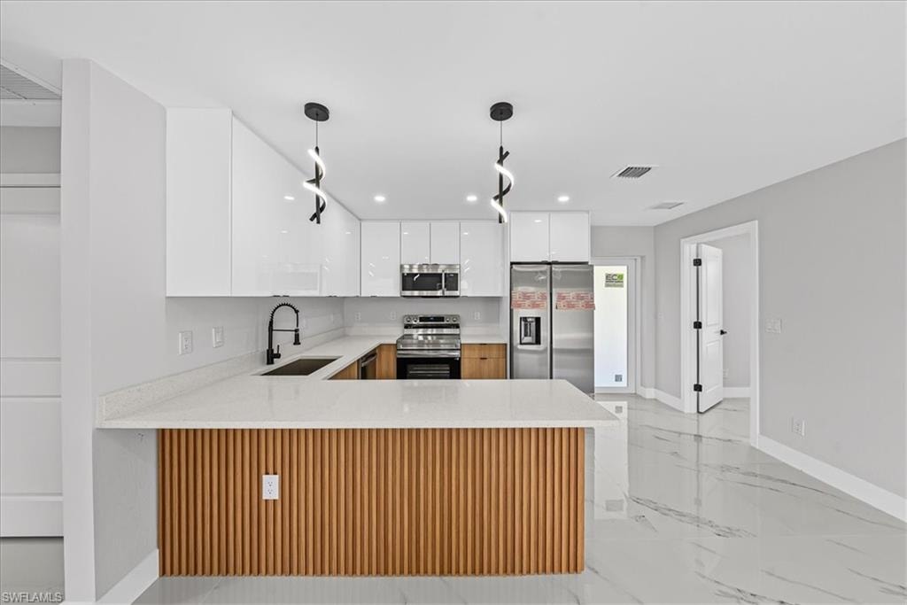 Kitchen featuring a breakfast bar with wood paneling, white shaker-style cabinetry, stainless steel appliances, and a matte black faucet